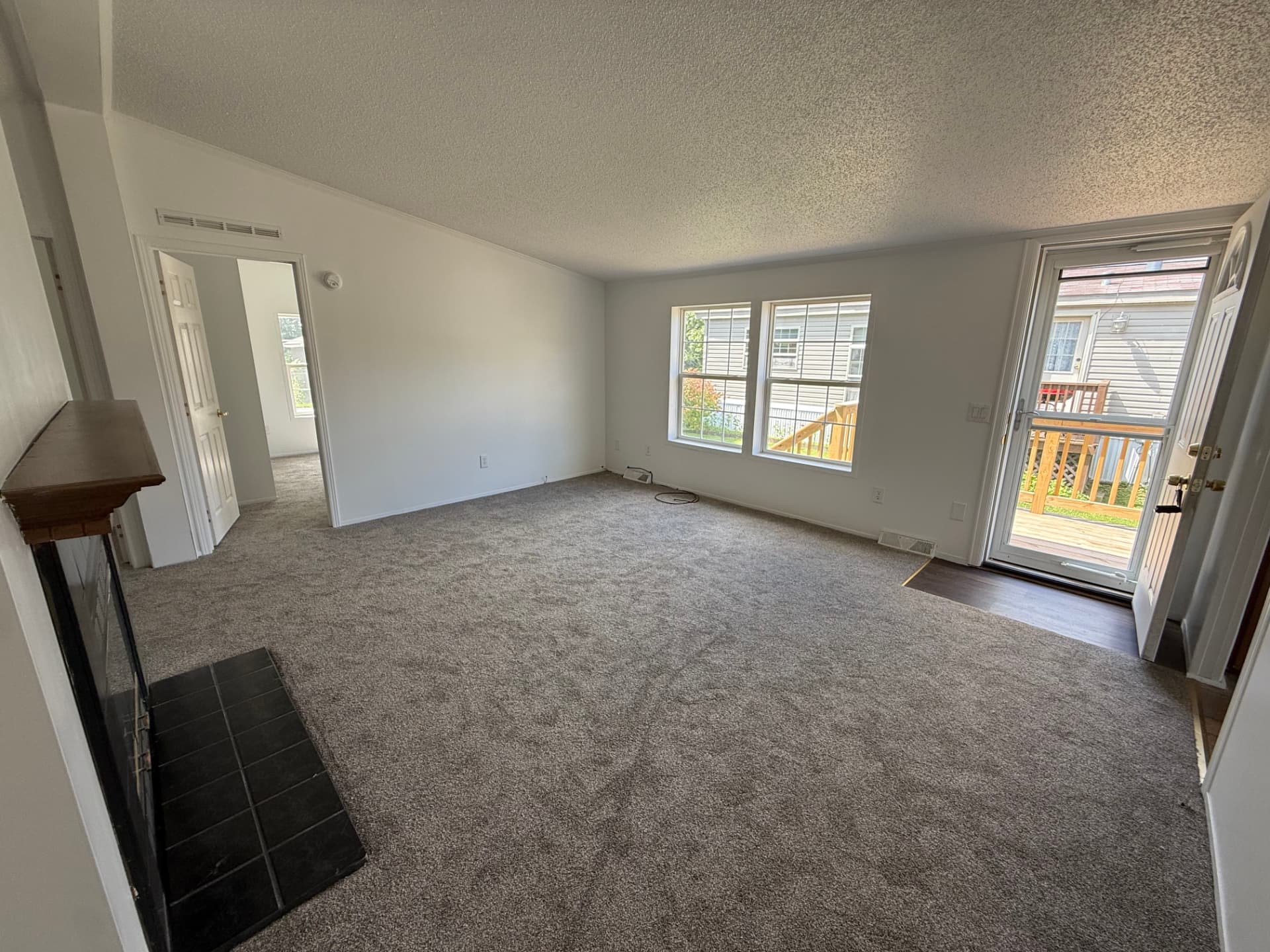 Carpeted living room at 40 Michael with double windows and door to the deck