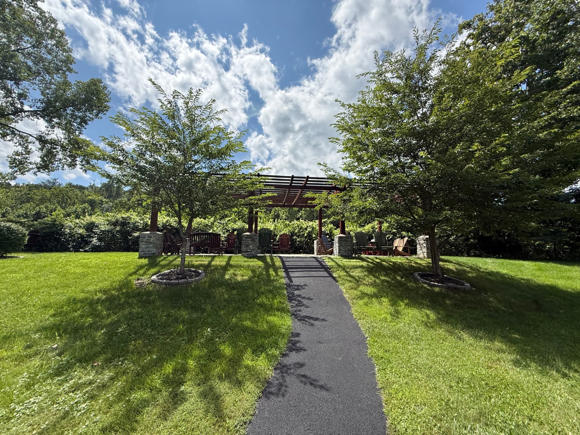 The walking path rising across the mown lawn toward the pergola at Tuscany Meadows