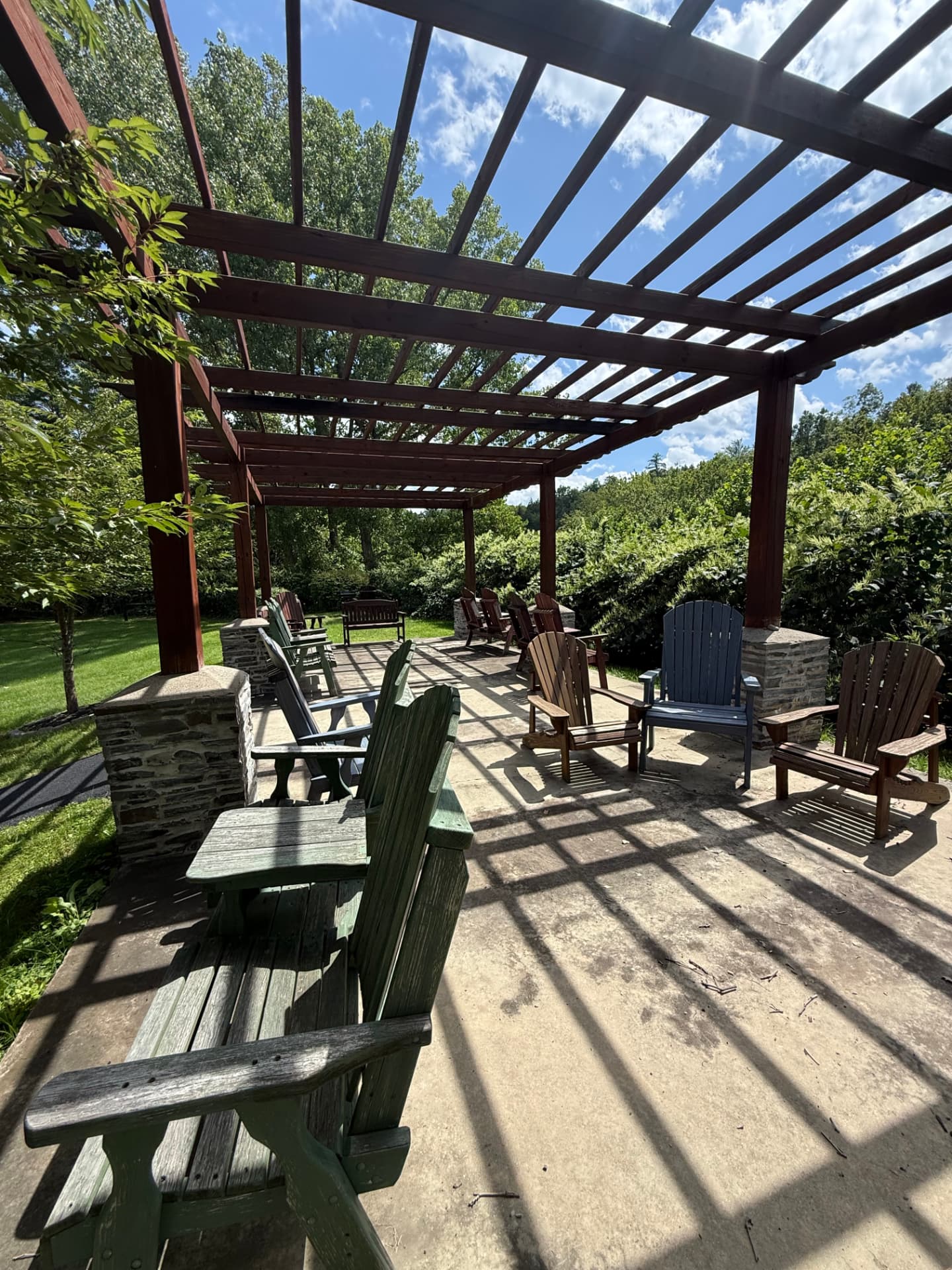 Wooden chairs in dappled light beneath the pergola at Tuscany Meadows